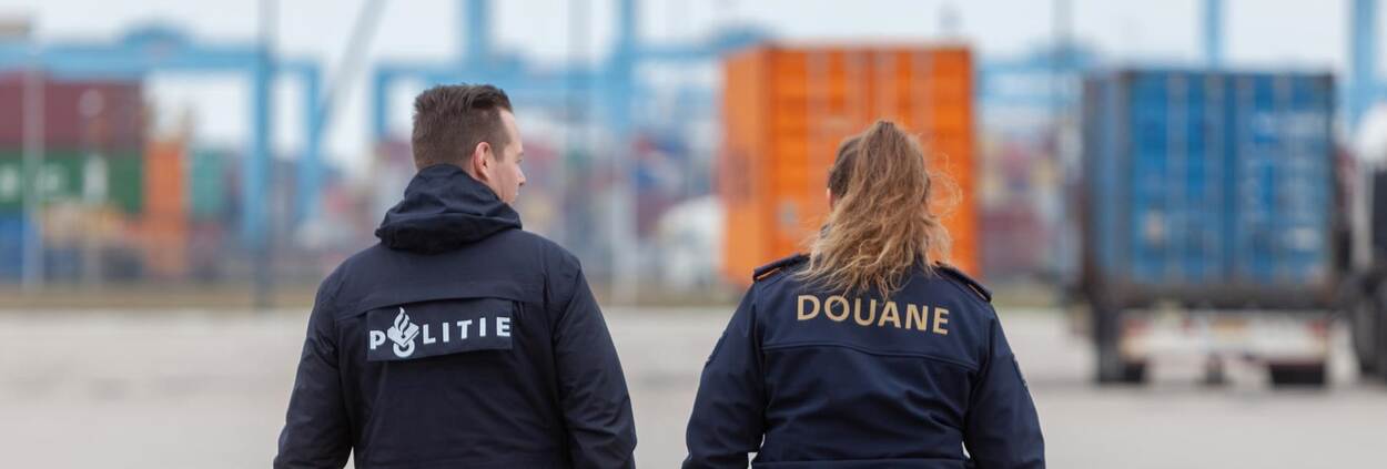 politieagent en douanier op de rug gezien met containers op de achtergrond