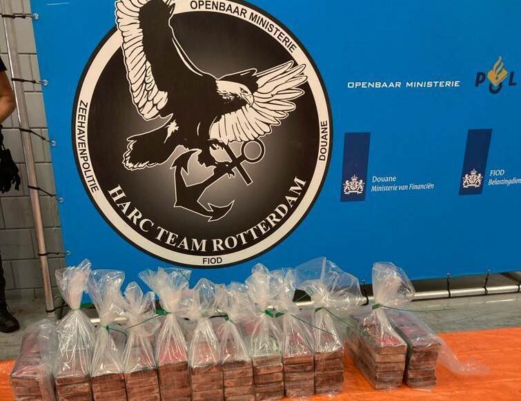 pakketten cocaïne uitgestald op de grond voor een banier van het HARC